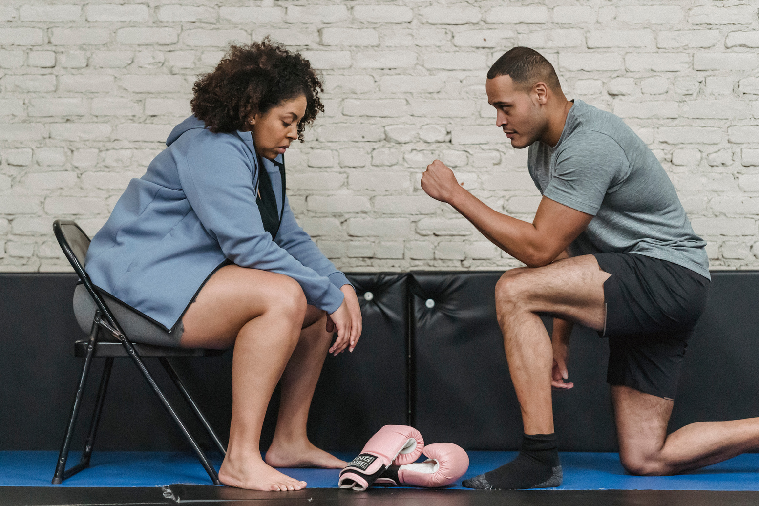 Black trainer explaining exercise to woman